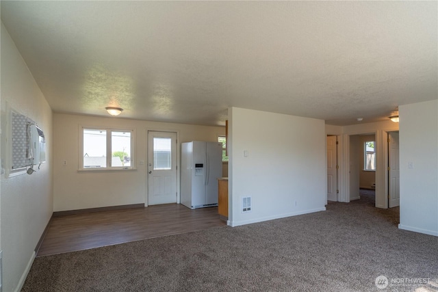unfurnished living room featuring carpet flooring, a wealth of natural light, visible vents, and baseboards