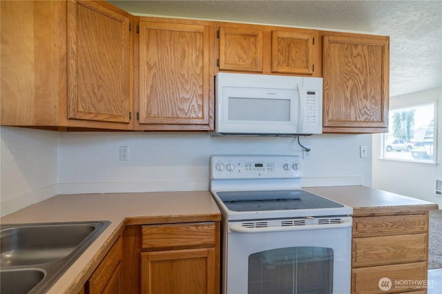 kitchen featuring white appliances, light countertops, a sink, and a textured ceiling