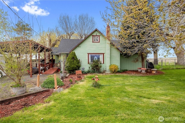 exterior space with a front yard, a chimney, fence, and roof with shingles