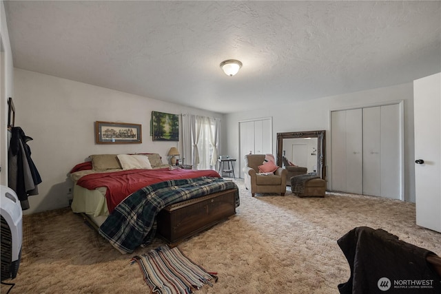carpeted bedroom featuring multiple closets and a textured ceiling
