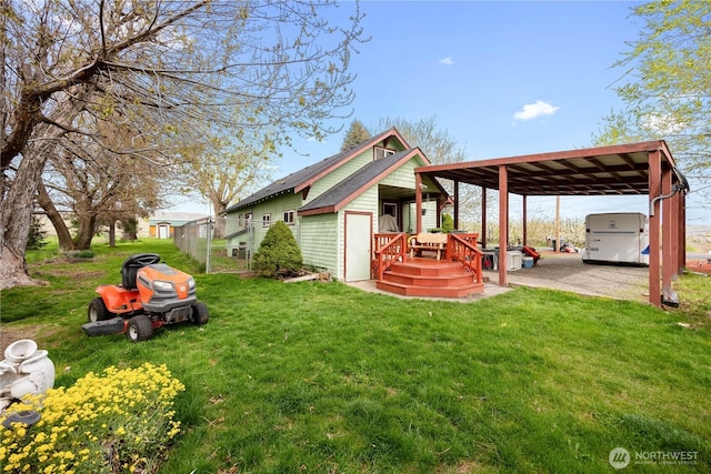 back of house featuring a yard, a detached carport, fence, and a gate