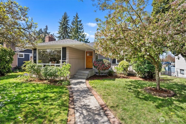 view of front of property with a chimney, a shingled roof, and a front yard
