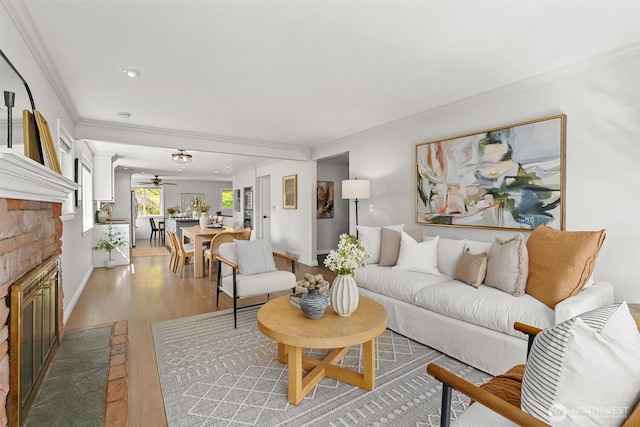living area featuring recessed lighting, light wood-type flooring, crown molding, a brick fireplace, and ceiling fan