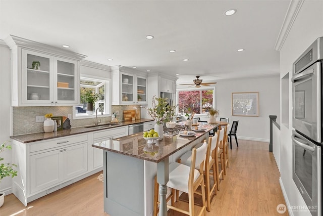 kitchen with a kitchen breakfast bar, a sink, backsplash, and light wood-style flooring