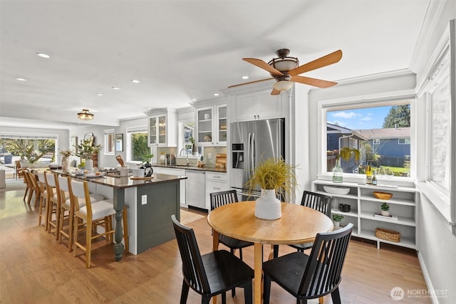 kitchen with white cabinets, stainless steel appliances, dark countertops, a sink, and a center island