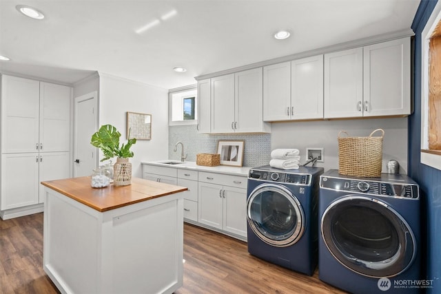 clothes washing area with dark wood finished floors, a sink, washer and clothes dryer, and recessed lighting
