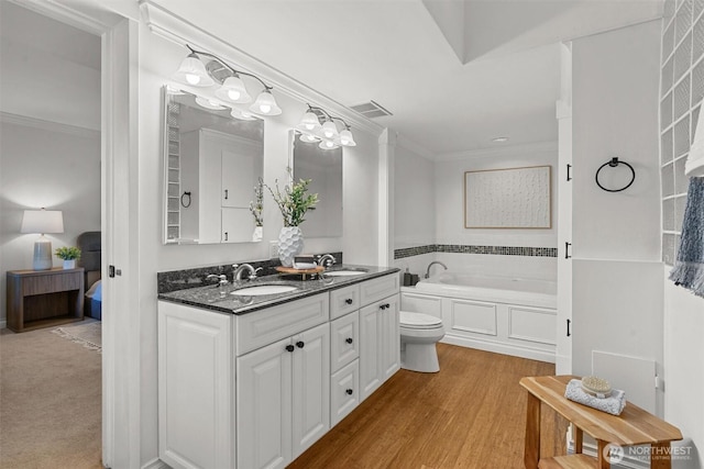 bathroom featuring double vanity, a garden tub, crown molding, and a sink