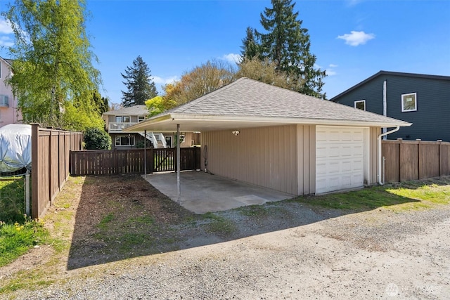 garage with fence and dirt driveway