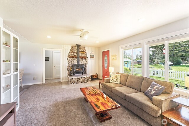 living area with carpet flooring, baseboards, recessed lighting, a ceiling fan, and a wood stove