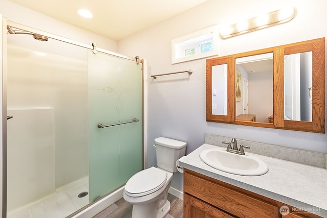 full bathroom with toilet, baseboards, wood finished floors, a shower stall, and vanity