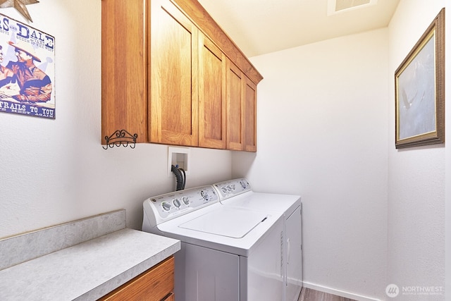 clothes washing area with separate washer and dryer, cabinet space, and visible vents