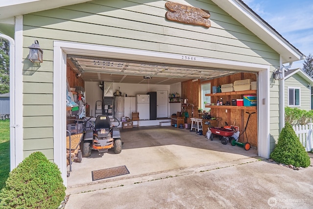 garage featuring concrete driveway and freestanding refrigerator