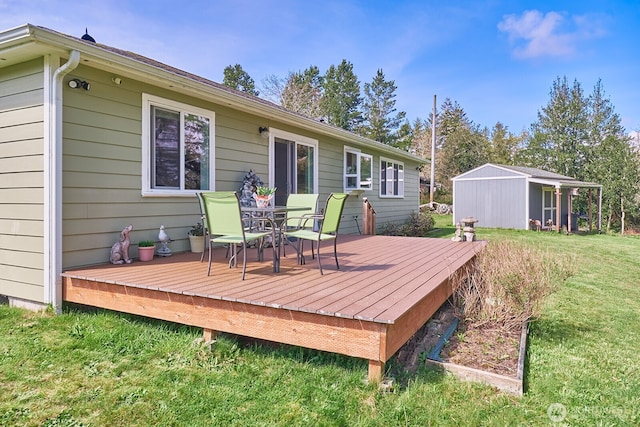 wooden terrace with a lawn, an outbuilding, and outdoor dining area