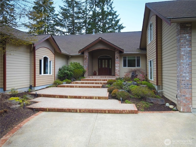 view of exterior entry featuring roof with shingles