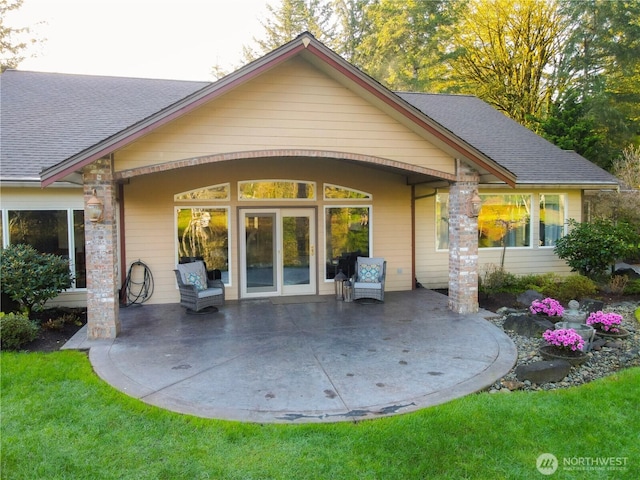 rear view of house featuring roof with shingles and a patio area