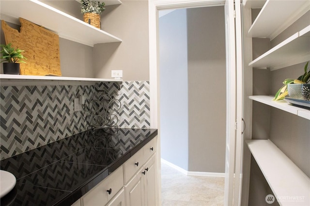 kitchen featuring backsplash, white cabinetry, dark countertops, and open shelves