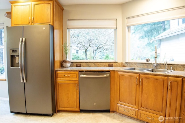 kitchen with brown cabinetry, appliances with stainless steel finishes, and a sink
