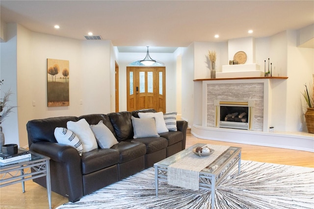 living area with a premium fireplace, wood finished floors, visible vents, and recessed lighting