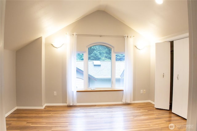 interior space featuring baseboards, wood finished floors, and lofted ceiling