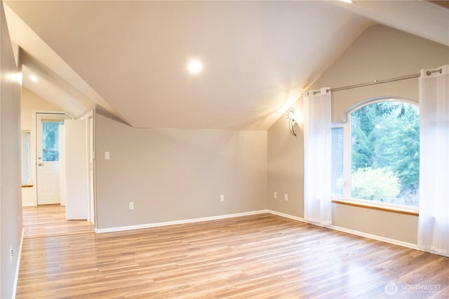 additional living space featuring light wood-style floors, baseboards, and vaulted ceiling