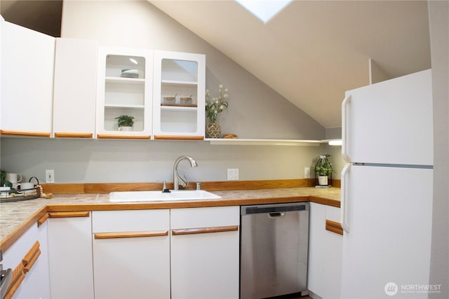 kitchen with stainless steel dishwasher, white cabinets, a sink, and freestanding refrigerator