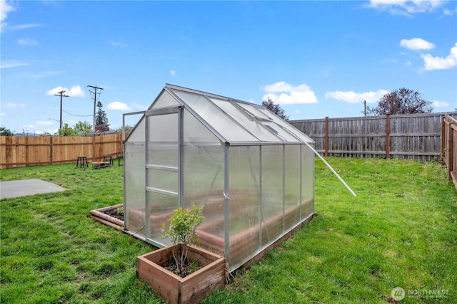 view of greenhouse with a yard and a fenced backyard