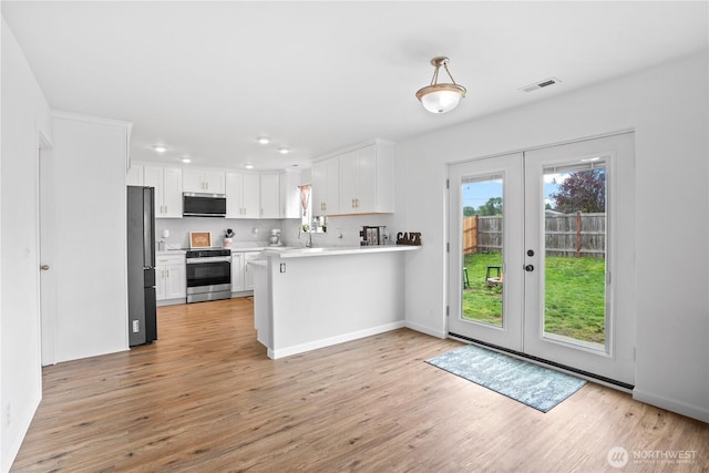 kitchen featuring a peninsula, light countertops, white cabinets, french doors, and stainless steel appliances