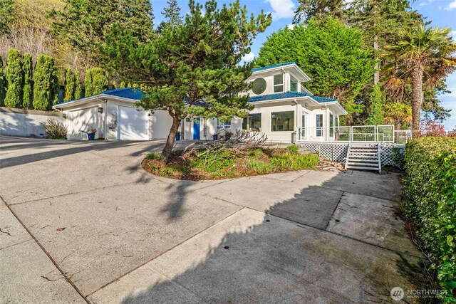 1192 E State Route 4, Cathlamet, WA 98612 - view of front facade featuring driveway, an attached garage, a deck, metal roof, and stucco siding