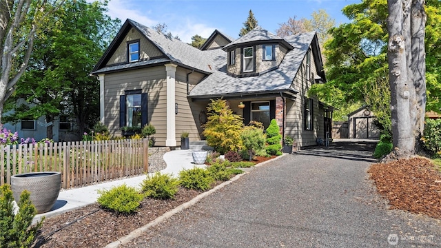 view of front of property with central air condition unit, fence, an outbuilding, and a shingled roof