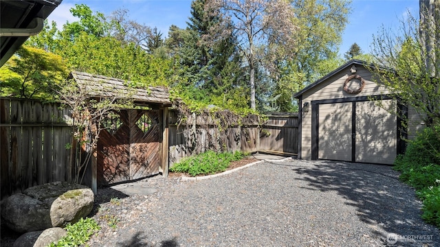 view of outdoor structure with a fenced backyard, an outbuilding, and driveway
