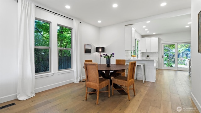 dining space featuring baseboards, visible vents, plenty of natural light, and light wood-type flooring