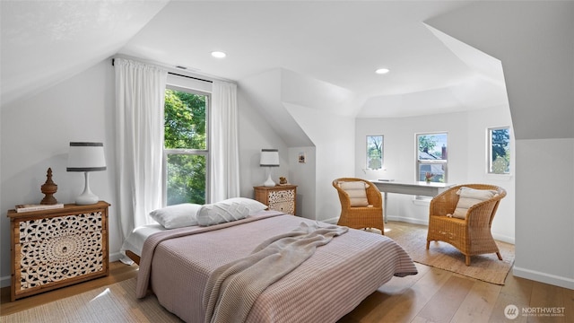 bedroom with baseboards, vaulted ceiling, multiple windows, and light wood-style flooring