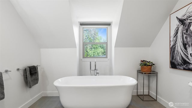 bathroom featuring baseboards, tile patterned floors, lofted ceiling, and a freestanding bath