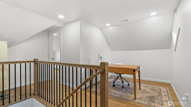 interior space with visible vents, vaulted ceiling, wood finished floors, an upstairs landing, and recessed lighting