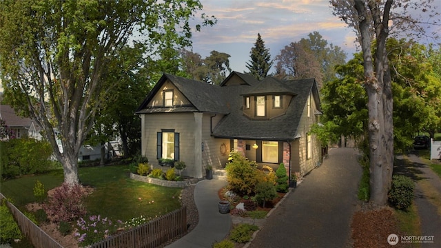 view of front facade featuring fence, a shingled roof, driveway, and a front yard