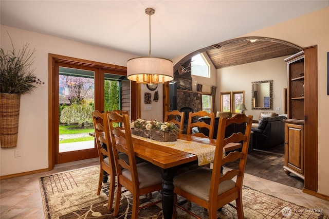 dining area with baseboards, arched walkways, plenty of natural light, and lofted ceiling