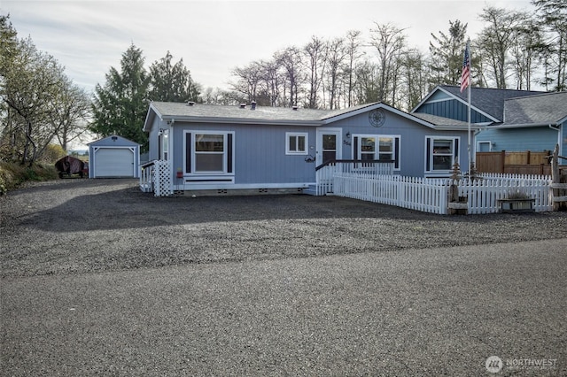 view of front facade featuring crawl space, a garage, dirt driveway, fence, and an outbuilding