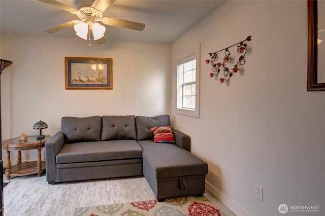 living room featuring baseboards, a ceiling fan, and wood finished floors