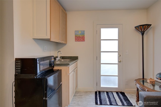 kitchen featuring baseboards, refrigerator, black microwave, dark countertops, and a sink
