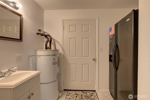laundry room featuring light wood-type flooring, a sink, and water heater