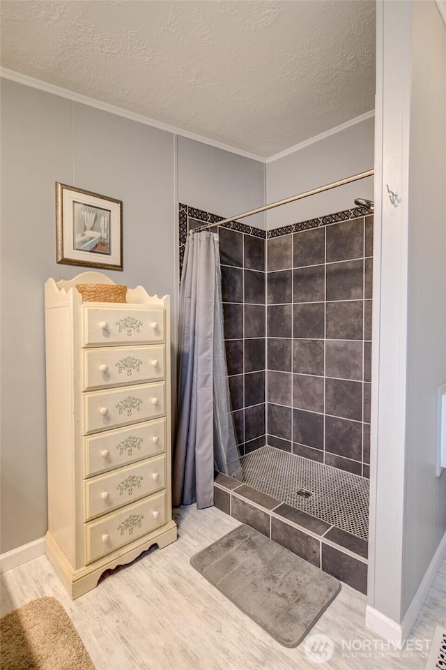 full bath with ornamental molding, a shower stall, and a textured ceiling