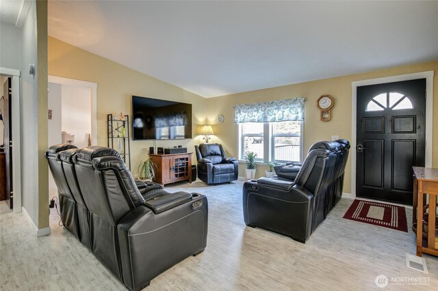 living room featuring visible vents, baseboards, light wood-type flooring, and vaulted ceiling