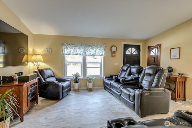 living area with baseboards, light wood-style floors, and lofted ceiling