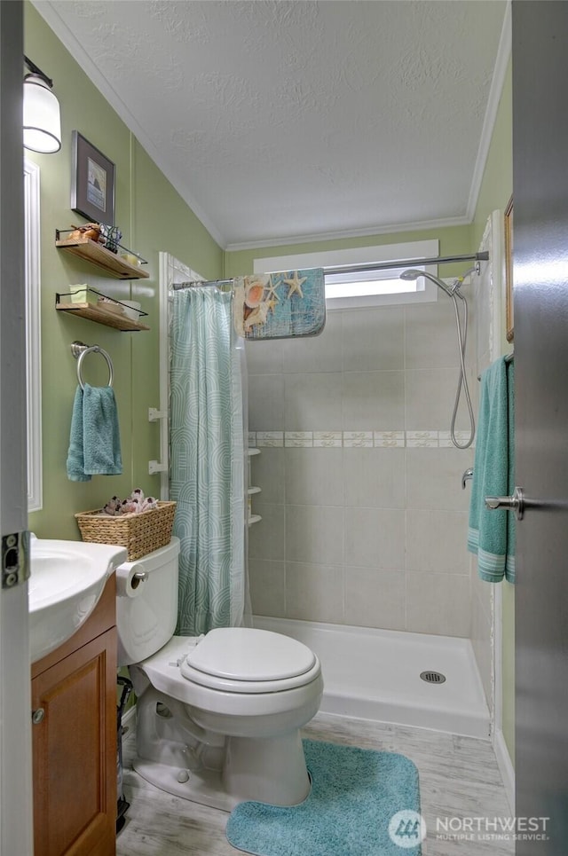 bathroom featuring toilet, ornamental molding, a tile shower, and vanity