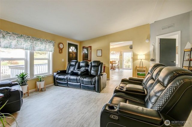 living area featuring light wood-style flooring, baseboards, visible vents, and a notable chandelier