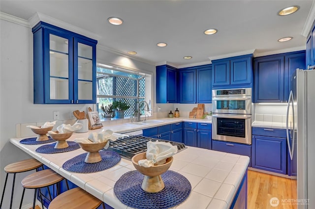 26225 Lake Wilderness Country Club Dr SE, Maple Valley, WA 98038 - kitchen featuring a sink, blue cabinets, glass insert cabinets, stainless steel appliances, and ornamental molding