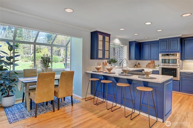26225 Lake Wilderness Country Club Dr SE, Maple Valley, WA 98038 - kitchen featuring double oven, blue cabinets, ornamental molding, and a kitchen breakfast bar