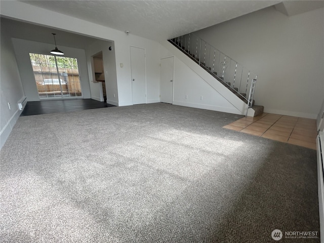 unfurnished living room featuring stairway, baseboards, and carpet