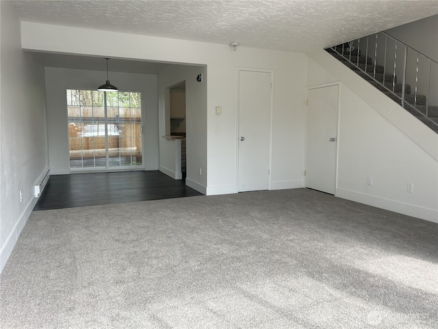 interior space featuring baseboards, dark colored carpet, a textured ceiling, and stairs