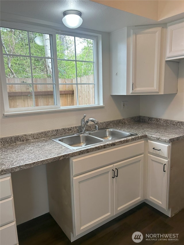 kitchen with a sink, dark wood-style flooring, and white cabinetry